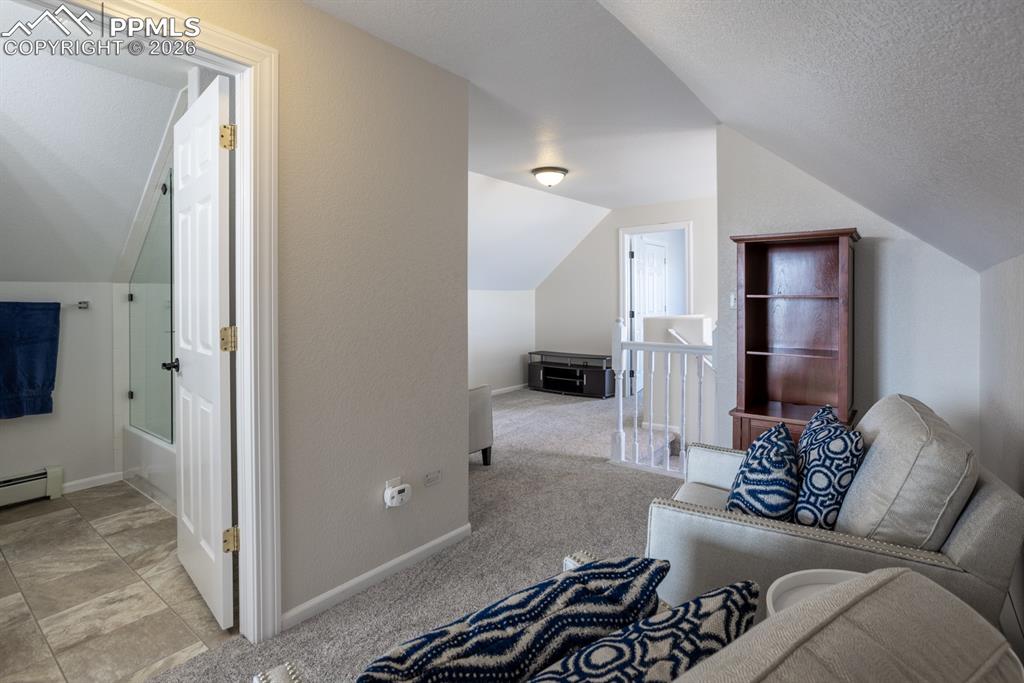Bonus room featuring lofted ceiling, a baseboard radiator, light colored carpet, a textured ceiling, and baseboards
