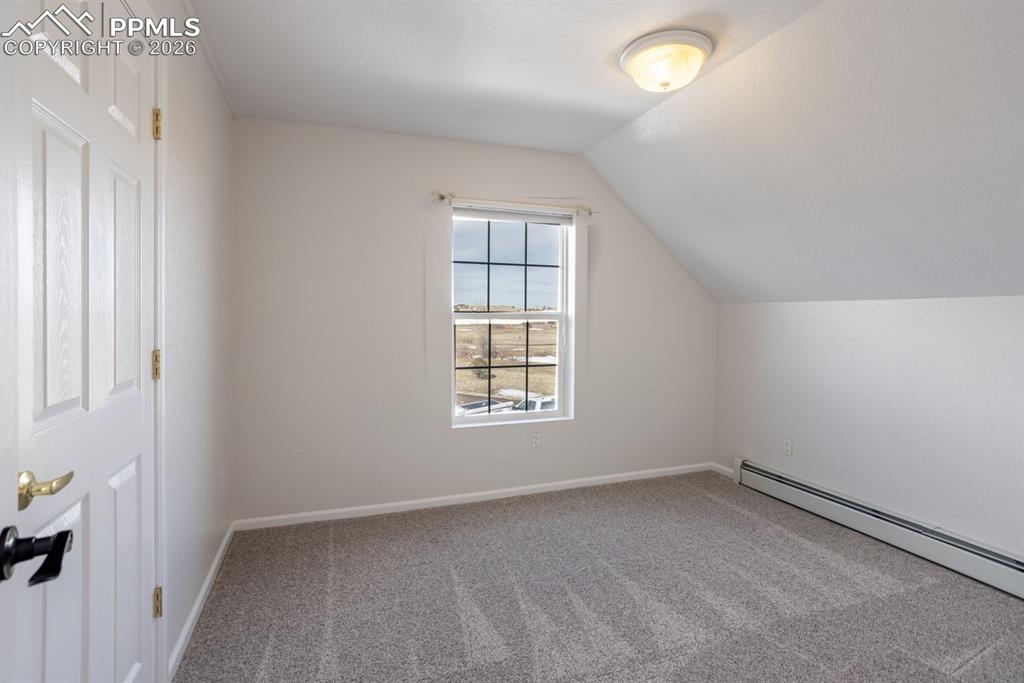 Additional living space featuring a baseboard heating unit, vaulted ceiling, carpet floors, and baseboards