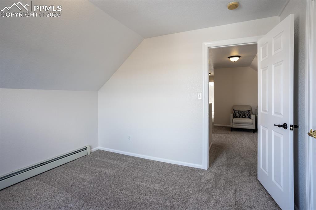 Bonus room with a baseboard heating unit, carpet floors, vaulted ceiling, and baseboards