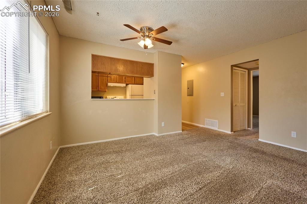 Living/Dining room with carpet floors and a ceiling fan