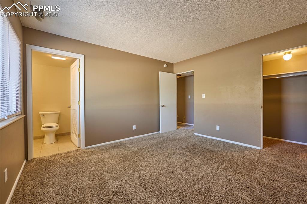 Master bedroom featuring a walk-in spacious closet, carpet and attached 1/2 bath