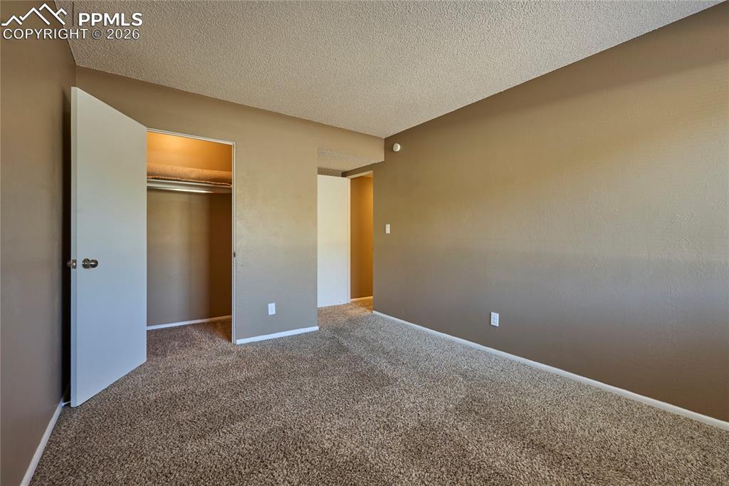 Unfurnished bedroom with a textured ceiling, carpet floors, and closet