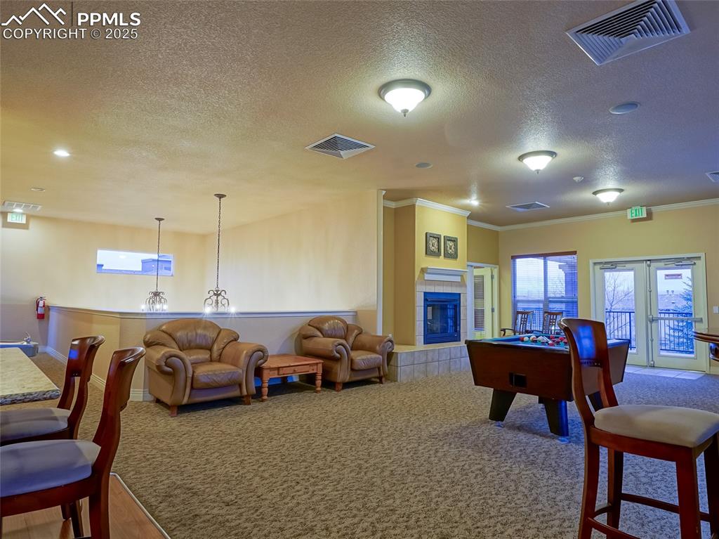 Community Game room and Kitchen with a tile fireplace View 2