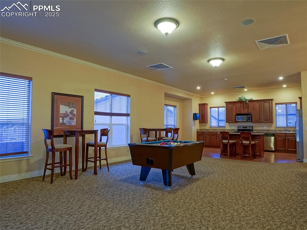 Community Game room and Kitchen with a tile fireplace View 2