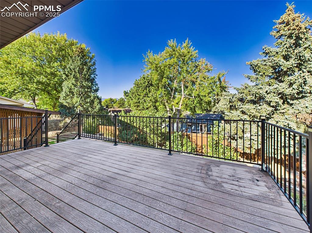 Spacious elevated deck with durable composite flooring and black metal railing, offering a private outdoor retreat surrounded by lush greenery.