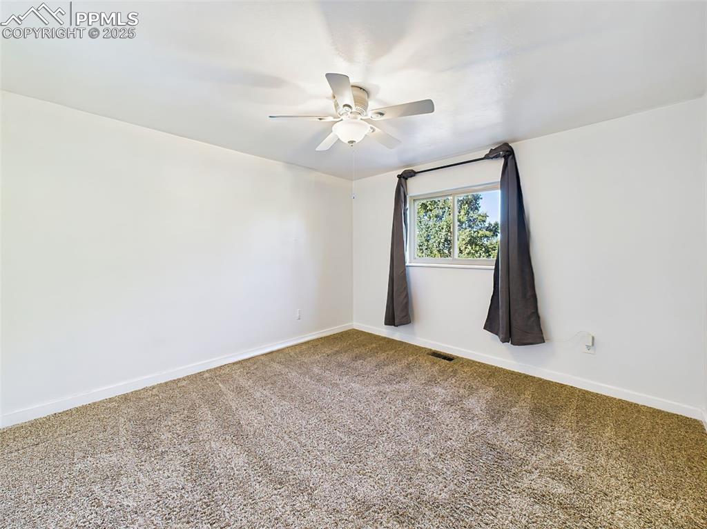 Spacious secondary bedroom with plush carpet, ample closet space, and bright window views.