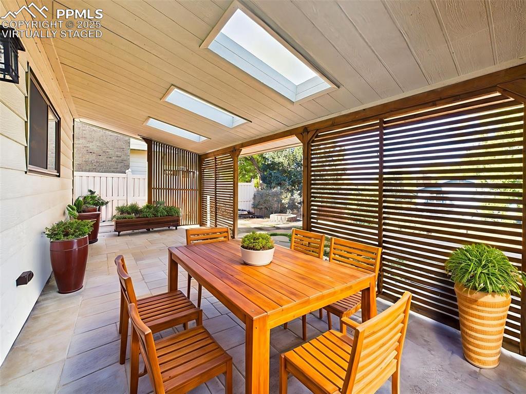 Virtually staged to highlight its entertaining potential, this covered patio features room for outdoor dining and potted plants.