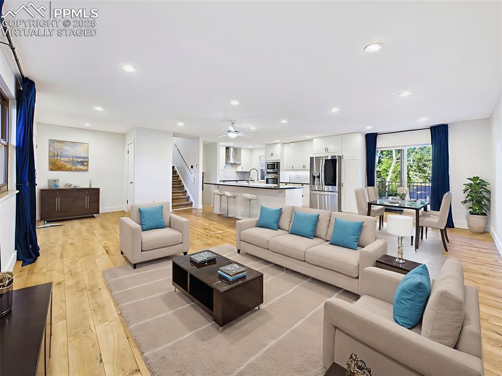 virtually staged view highlights the generous scale of the space, easily fitting a dining area, lounge, and bar seating at the kitchen island.