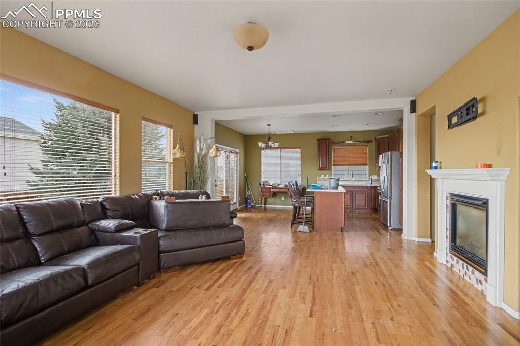 Living room with a glass covered fireplace, light wood-style floors, and suspended lighting
