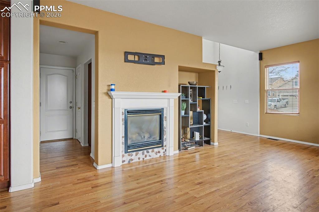 Unfurnished living room featuring a glass covered fireplace and light wood-style flooring