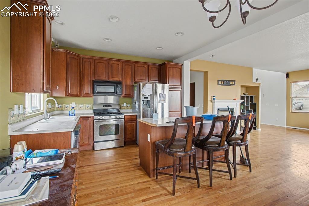 Kitchen featuring healthy amount of natural light, stainless steel appliances, a kitchen bar, and light wood finished floors