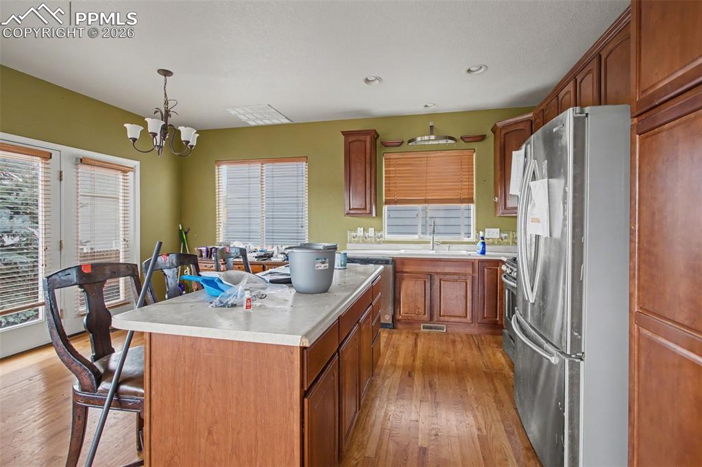 Kitchen with stainless steel appliances, light countertops, light wood-style floors, wood finish cabinetry, and a kitchen breakfast bar