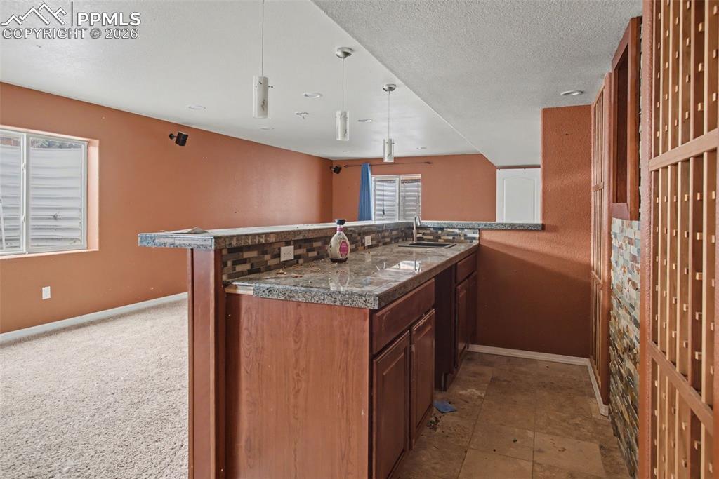Kitchen featuring wood finish cabinetry, a textured ceiling, pendant lighting, and tile countertops