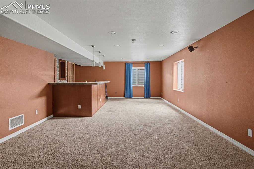Indoor wet bar featuring light carpet and a textured wall