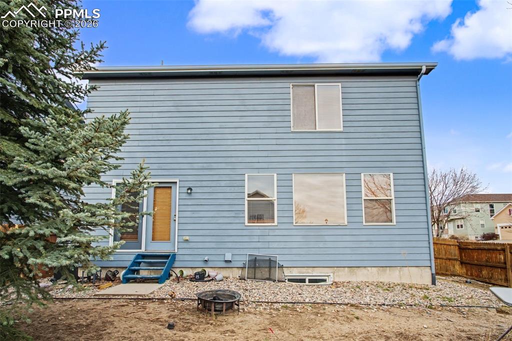 Back of house with entry steps and an outdoor fire pit