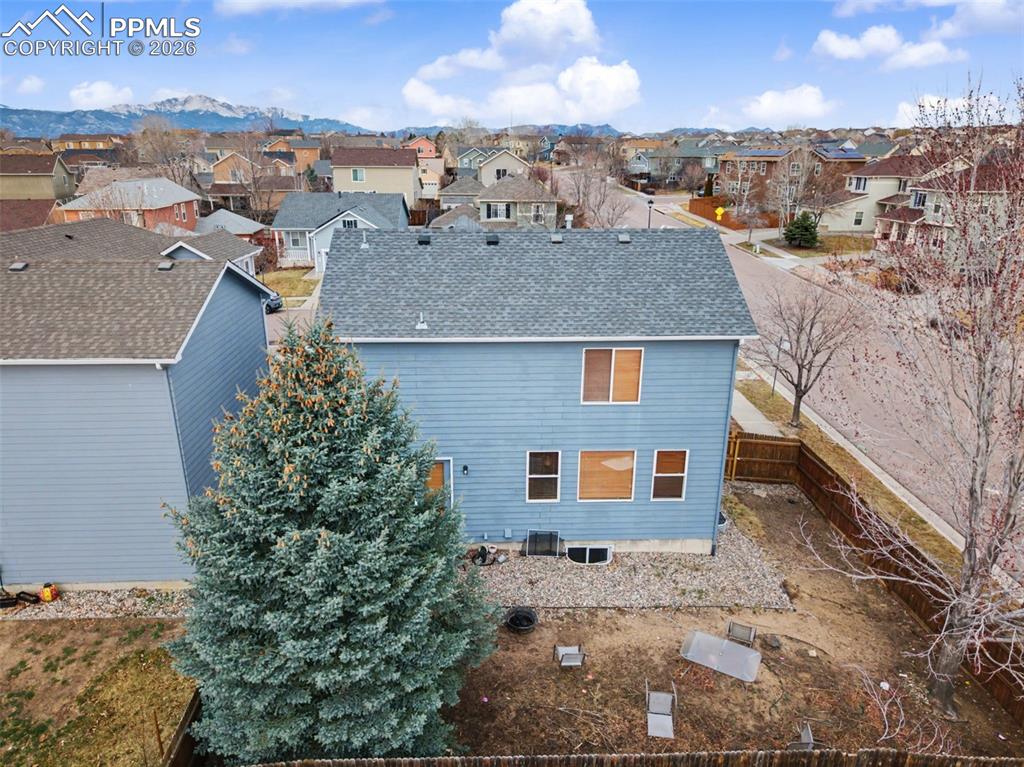 Rear view of property featuring a fenced backyard, roof with shingles, and a residential view