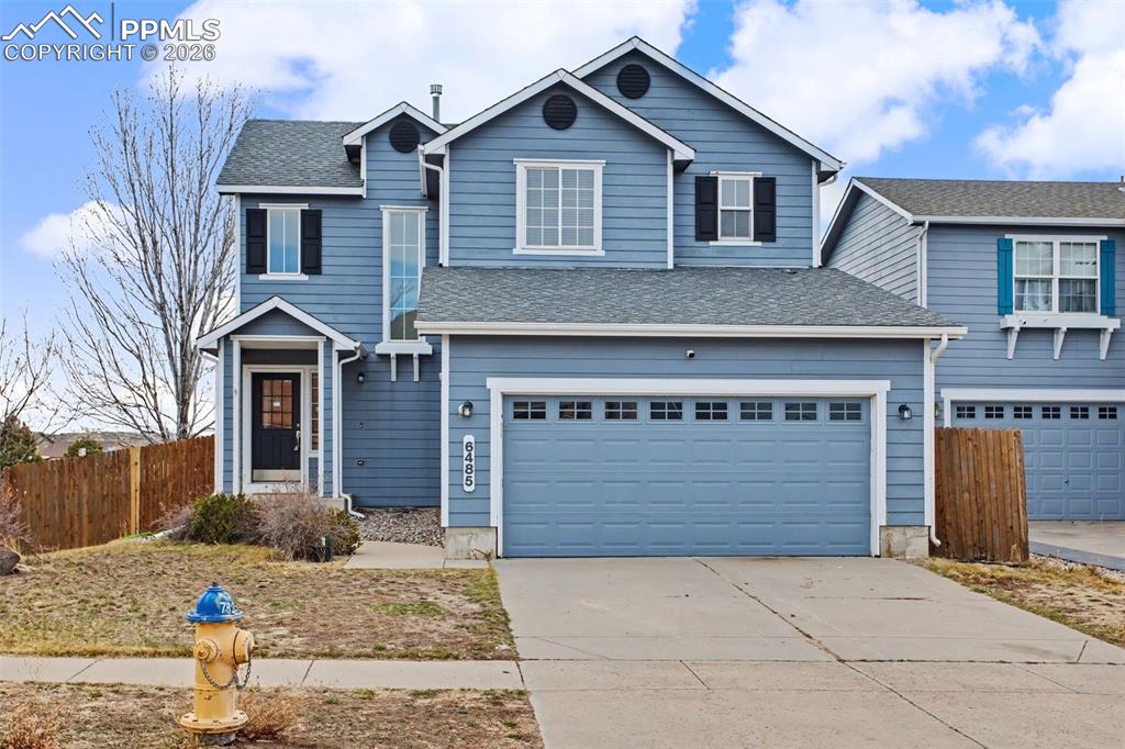 Traditional home featuring concrete driveway, a garage, and roof with shingles