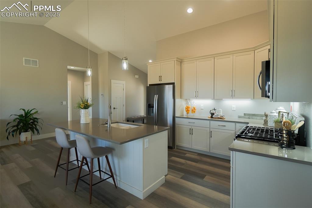 Kitchen featuring white cabinetry, hardwood / LTV style floors, a kitchen island with sink, and sink
