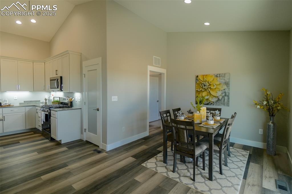 Dining area featuring LTV wood-type flooring and high vaulted ceiling