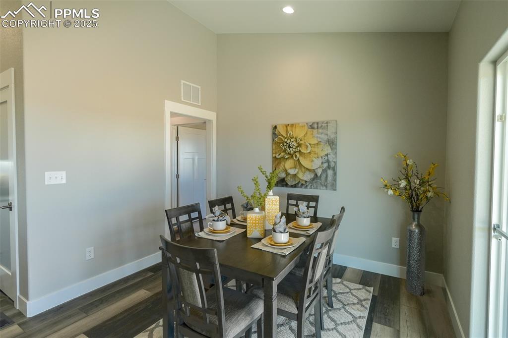 Dining area with dark LTV/ wood-style floors and lofted ceiling