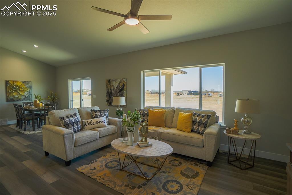 Living room featuring vaulted ceiling, LTV / wood-style floors, ceiling fan, and a wealth of natural light