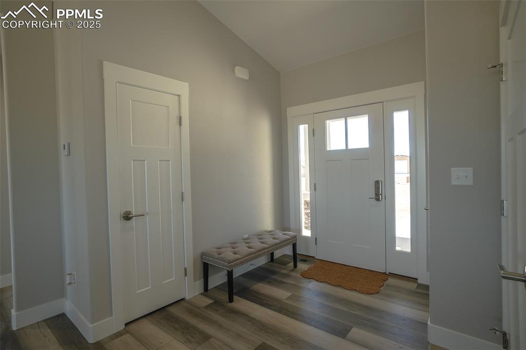 Entrance foyer featuring LTV/ wood-style flooring and lofted ceiling