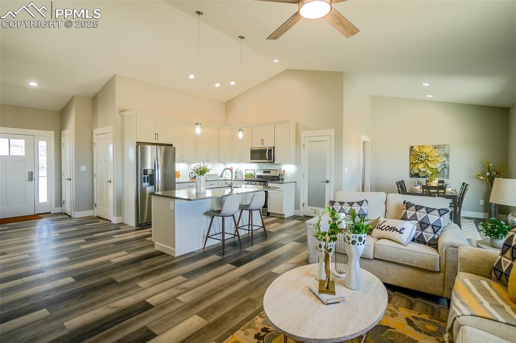 Living room featuring sink,  LTV/ wood-style flooring, ceiling fan, and high vaulted ceiling