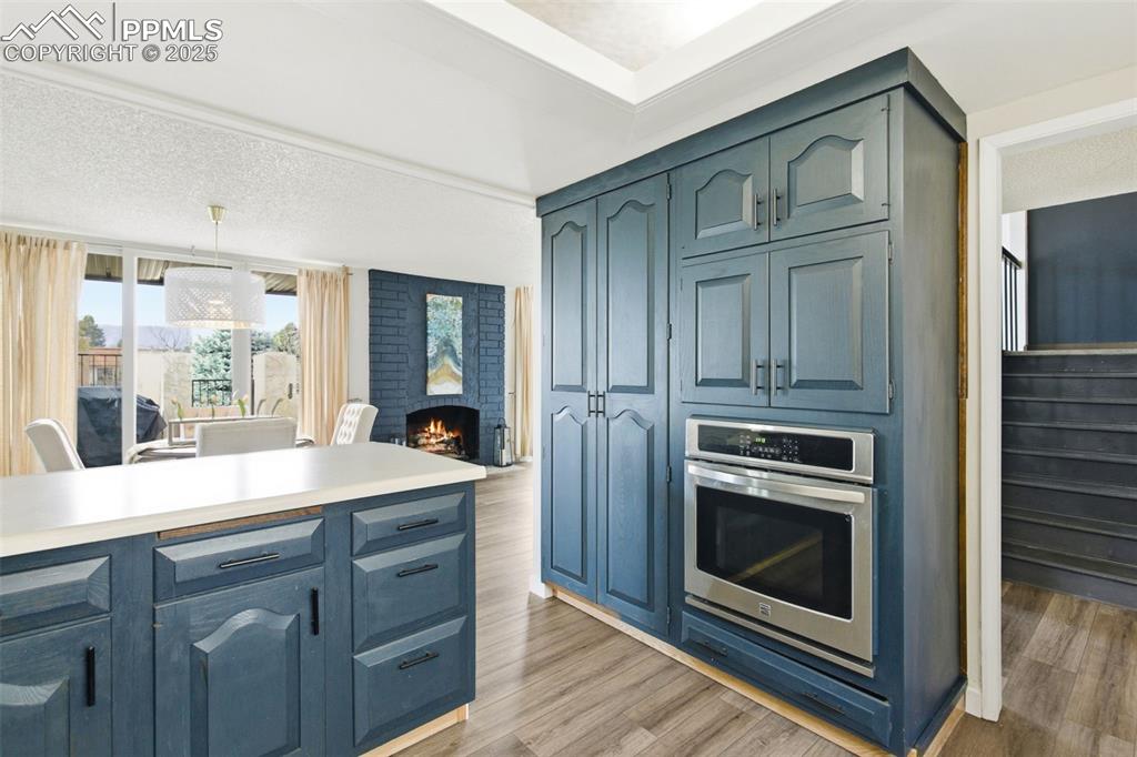 Kitchen featuring oven, pendant lighting, a brick fireplace, light countertops, and light wood-style floors