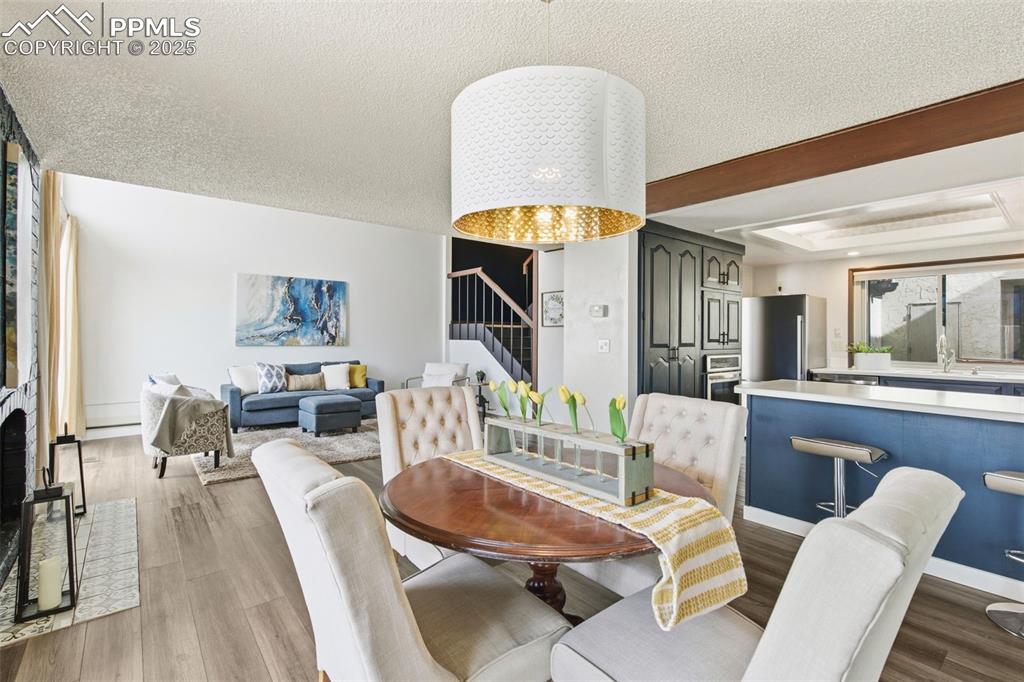 Dining room featuring stairs, a textured ceiling, dark wood-style flooring, and a tray ceiling