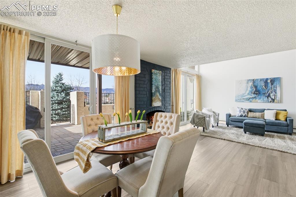 Dining room featuring healthy amount of natural light, wood finished floors, a textured ceiling, a brick fireplace, and floor to ceiling windows