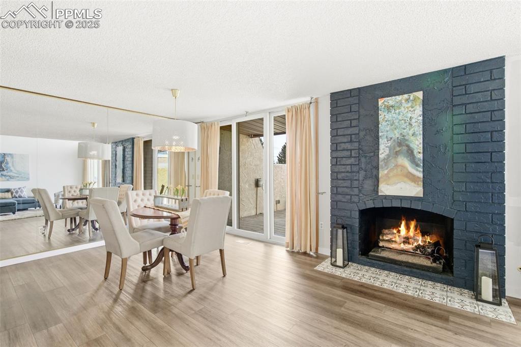 Dining room featuring a brick fireplace, a textured ceiling, light wood finished floors, and expansive windows