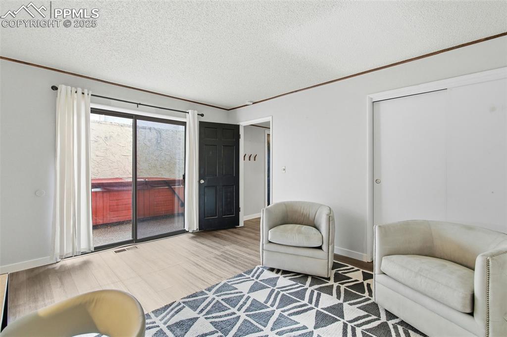 Living area with wood finished floors, a textured ceiling, and ornamental molding