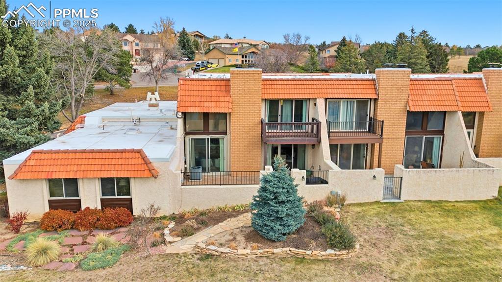 Back of house featuring a chimney, a balcony, and stucco siding