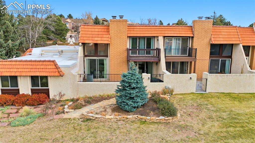 Back of property featuring a tiled roof, a chimney, a balcony, and a gate