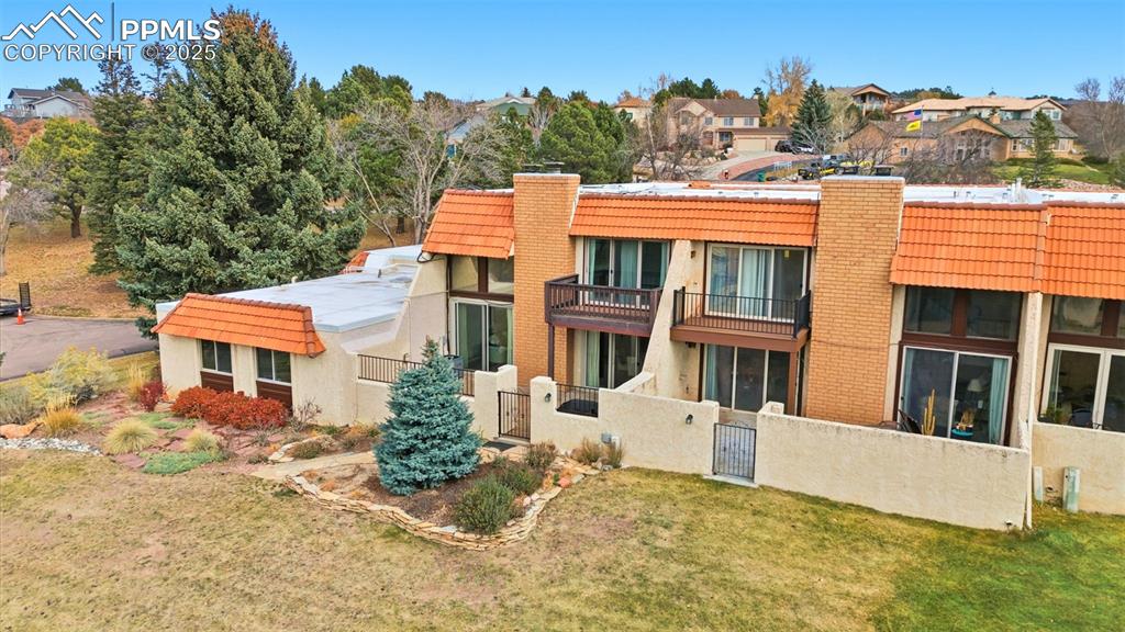Rear view of property with a chimney, a balcony, a gate, stucco siding, and a tiled roof