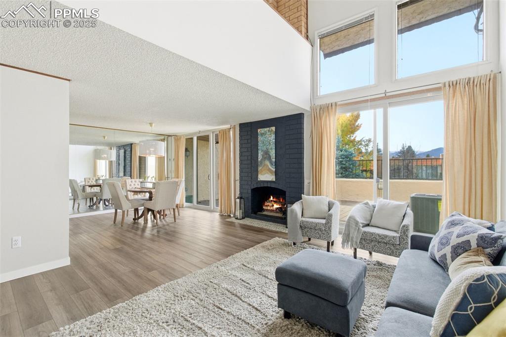 Living area featuring plenty of natural light, wood finished floors, a fireplace and a towering ceiling