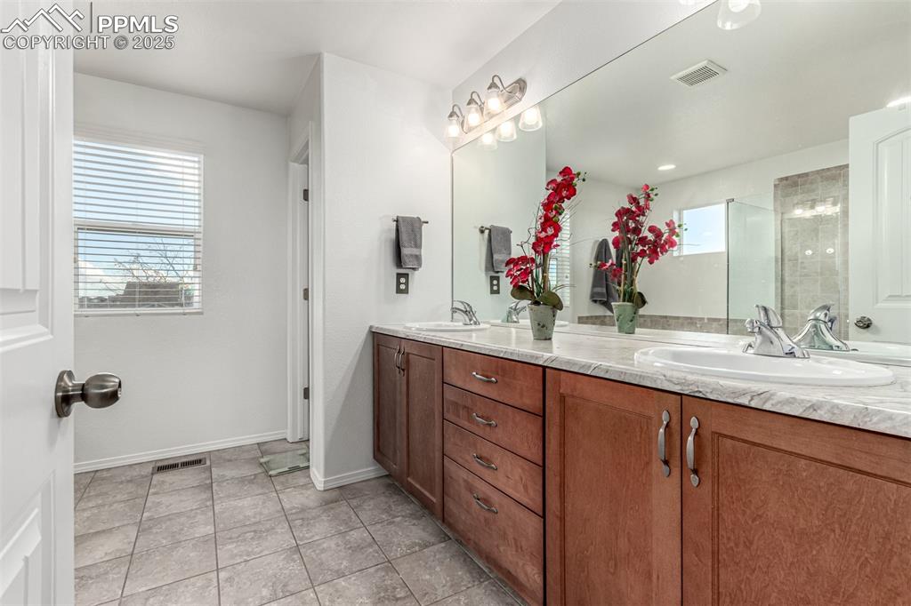 Full bathroom with double vanity, a shower stall, and light tile patterned floors