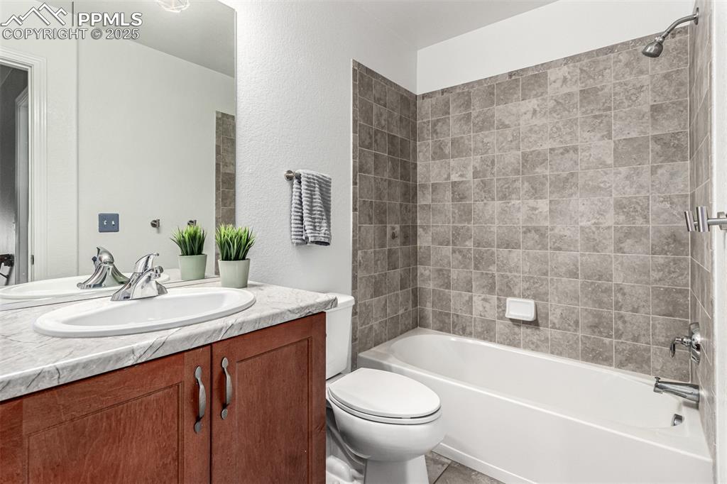 Full bathroom featuring vanity, shower / bath combination, a textured wall, and light tile patterned flooring