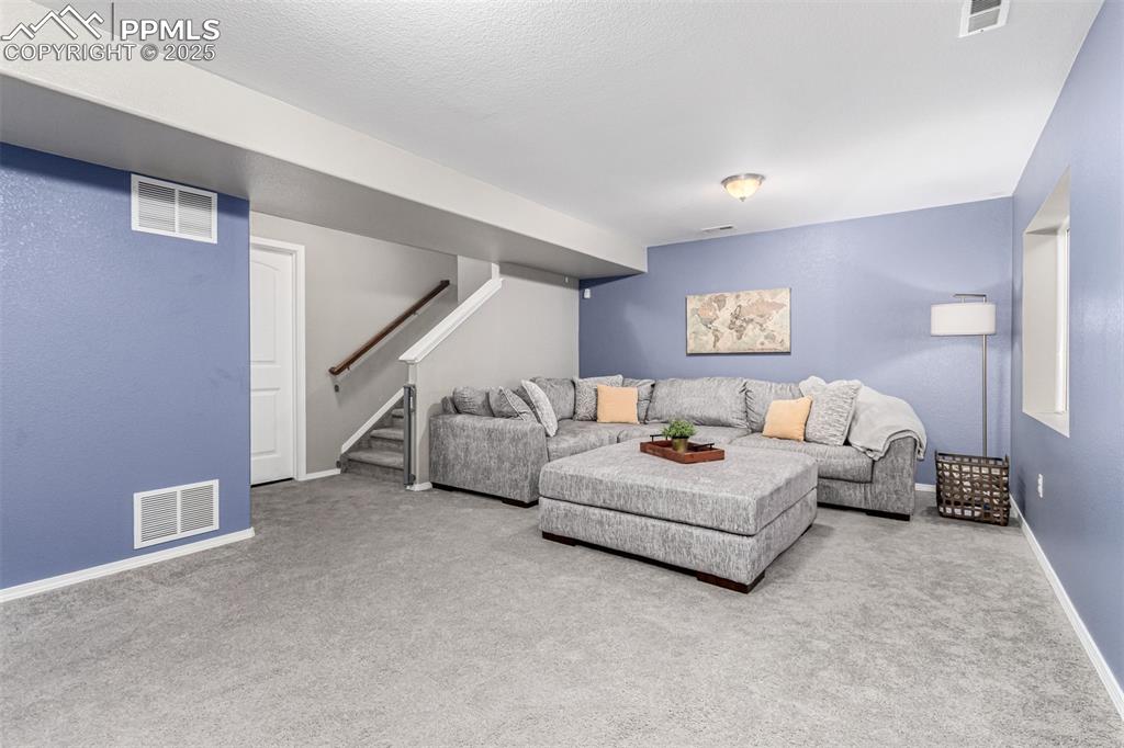 Carpeted living area featuring stairway and baseboards