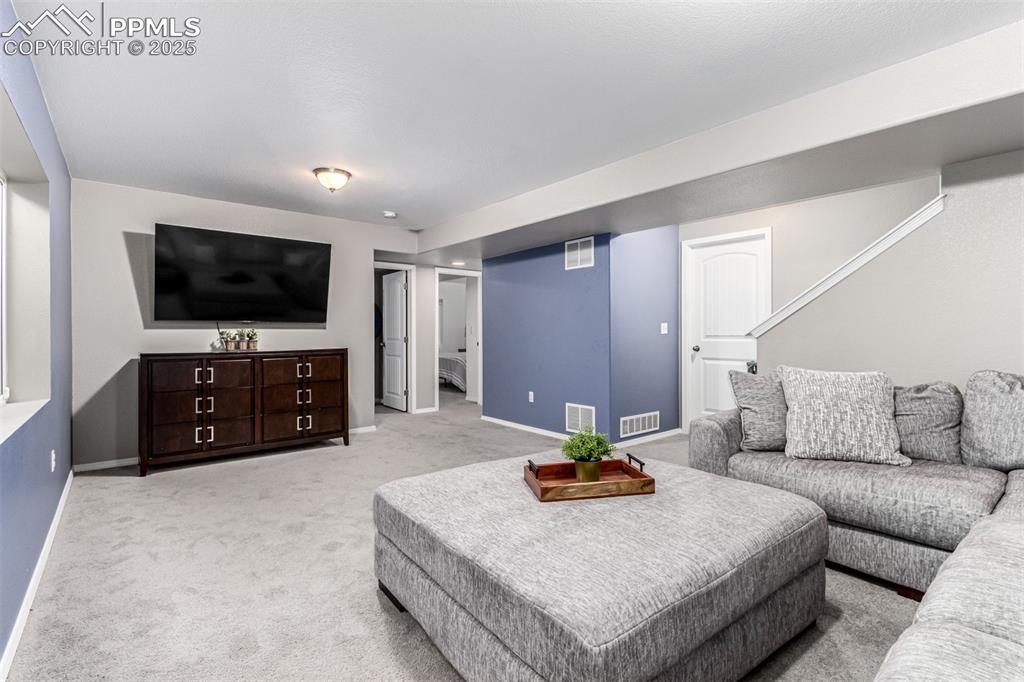 Living area with light colored carpet and stairway