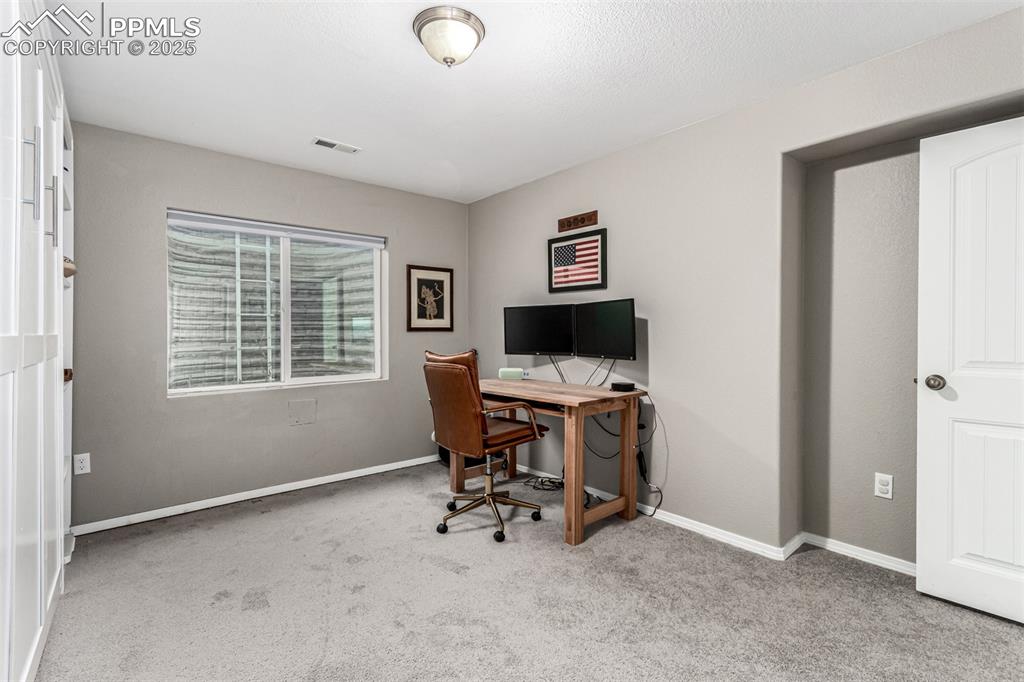 Home office with light carpet and baseboards