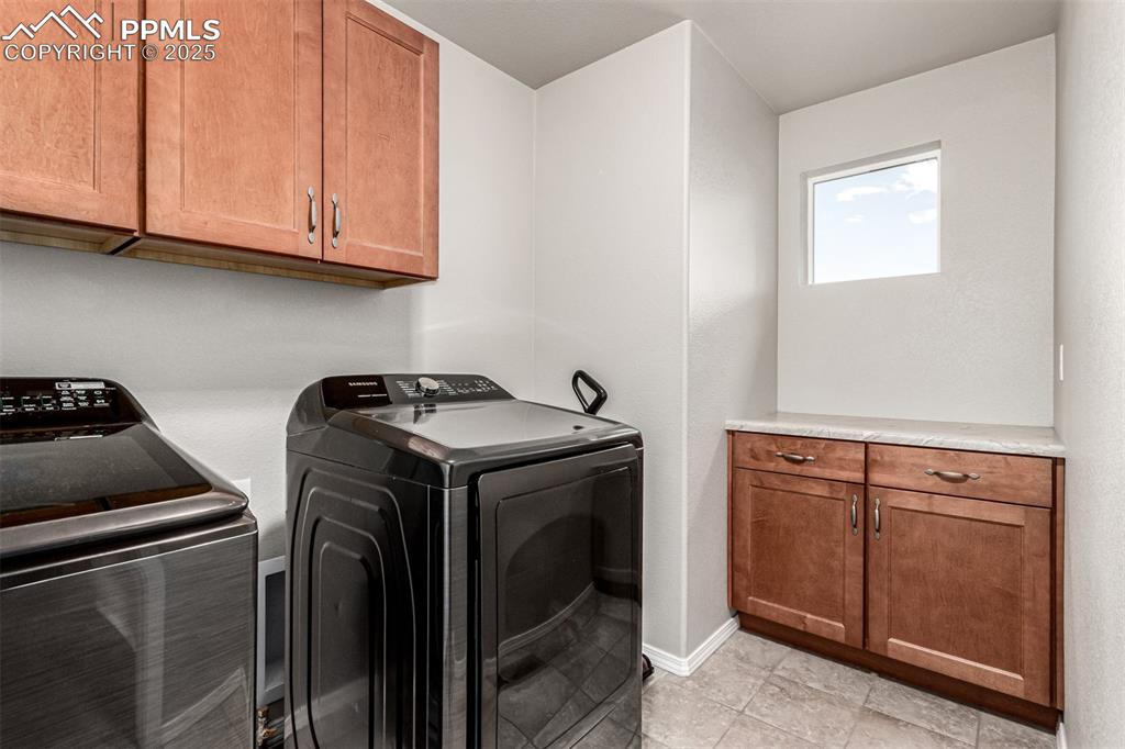 Laundry room with cabinet space, separate washer and dryer, and light tile patterned floors