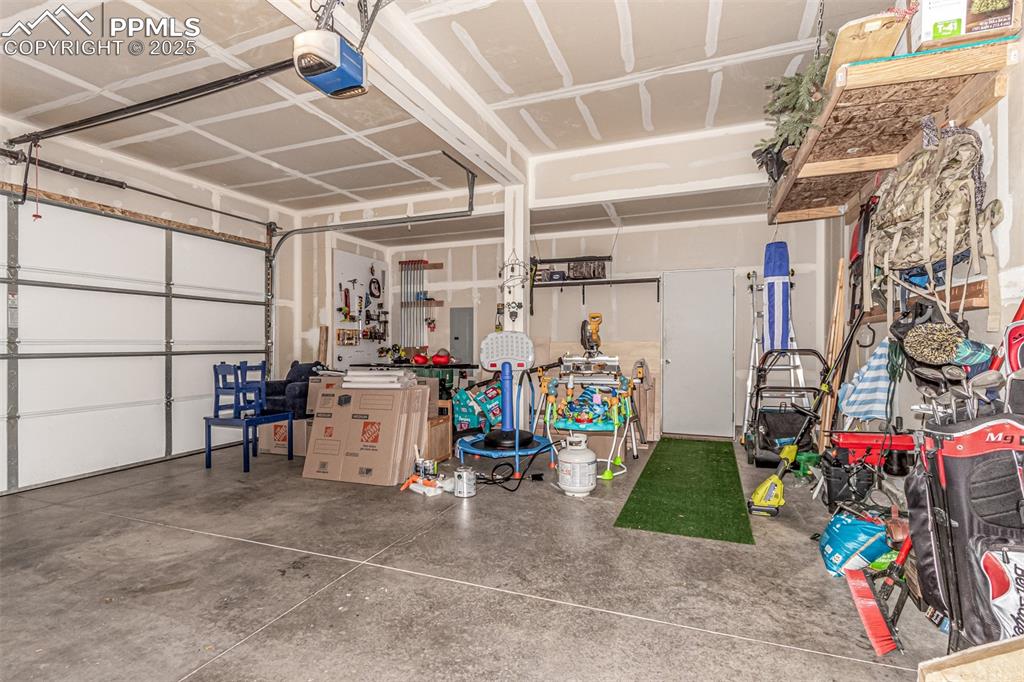 Garage featuring a garage door opener and electric panel