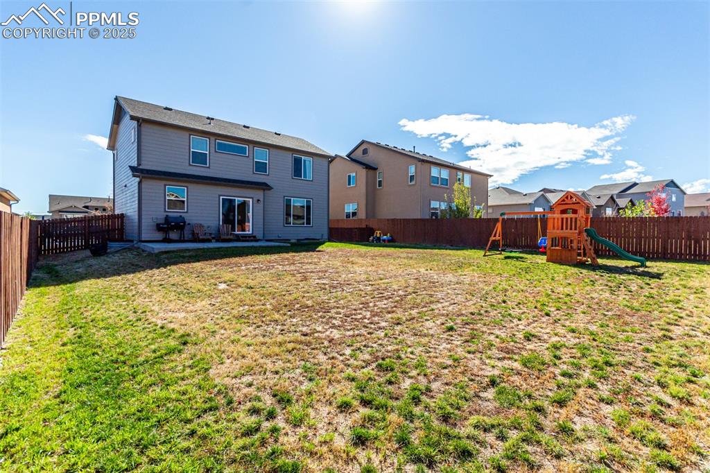 Rear view of house featuring a fenced backyard, a patio, a residential view, and a playground