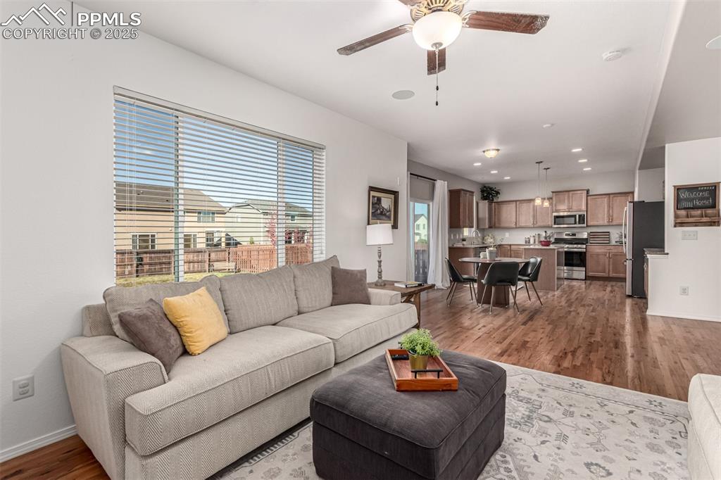Living room with dark wood-type flooring, recessed lighting, and ceiling fan