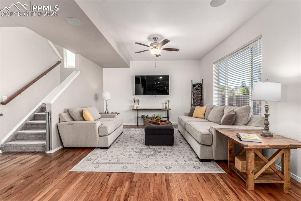 Living room featuring stairs, wood finished floors, and a ceiling fan
