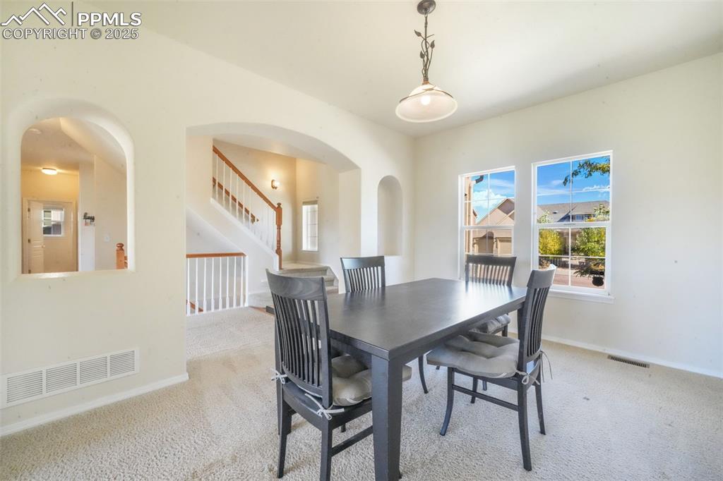 Carpeted dining area featuring arched walkways and baseboards