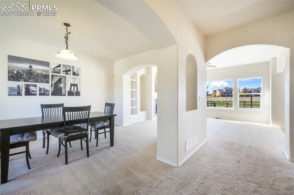 Dining space featuring light carpet, arched walkways, and built in features