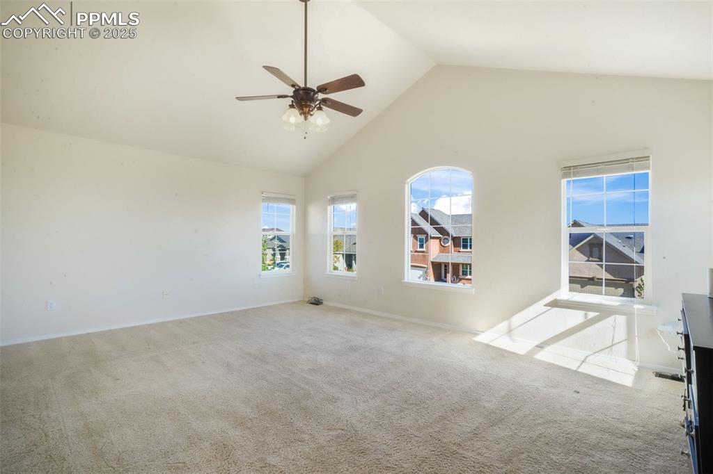Unfurnished room with high vaulted ceiling, carpet, and a ceiling fan