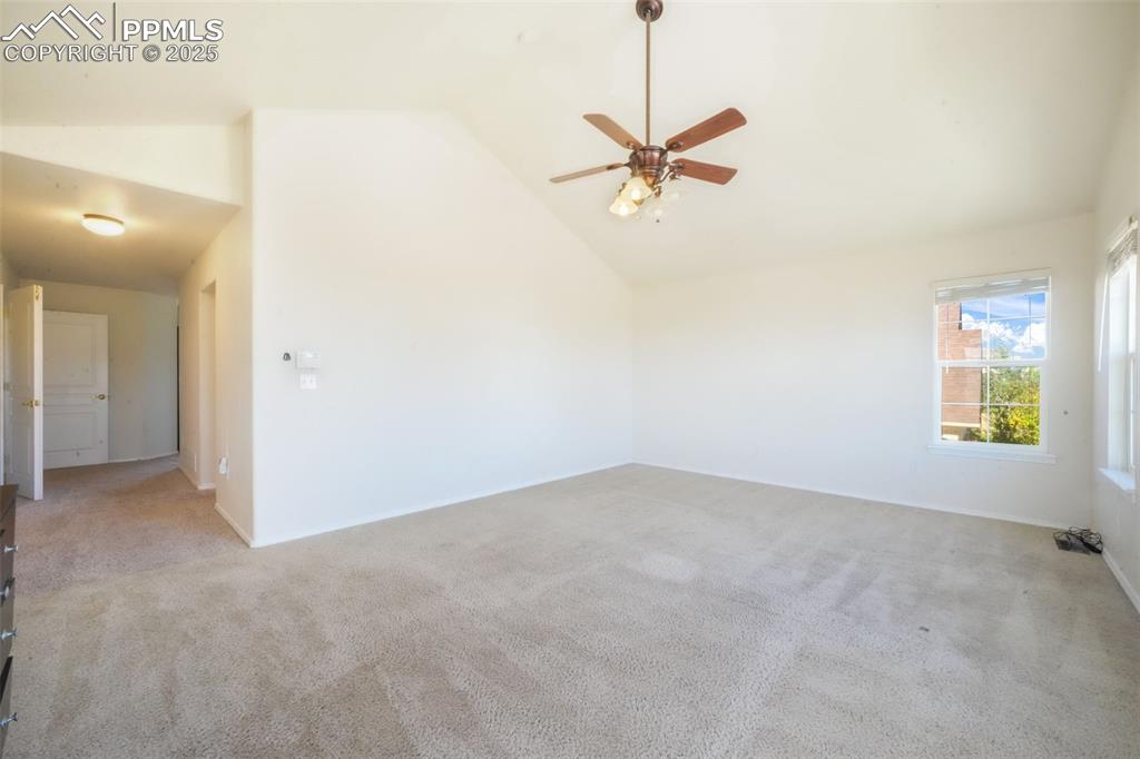 Spare room featuring carpet, ceiling fan, and high vaulted ceiling